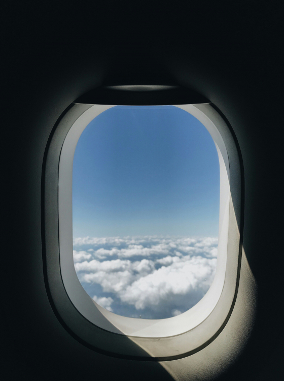 Ausblick aus dem Flugzeugfenster &uuml;ber den Wolken auf einer Reise.