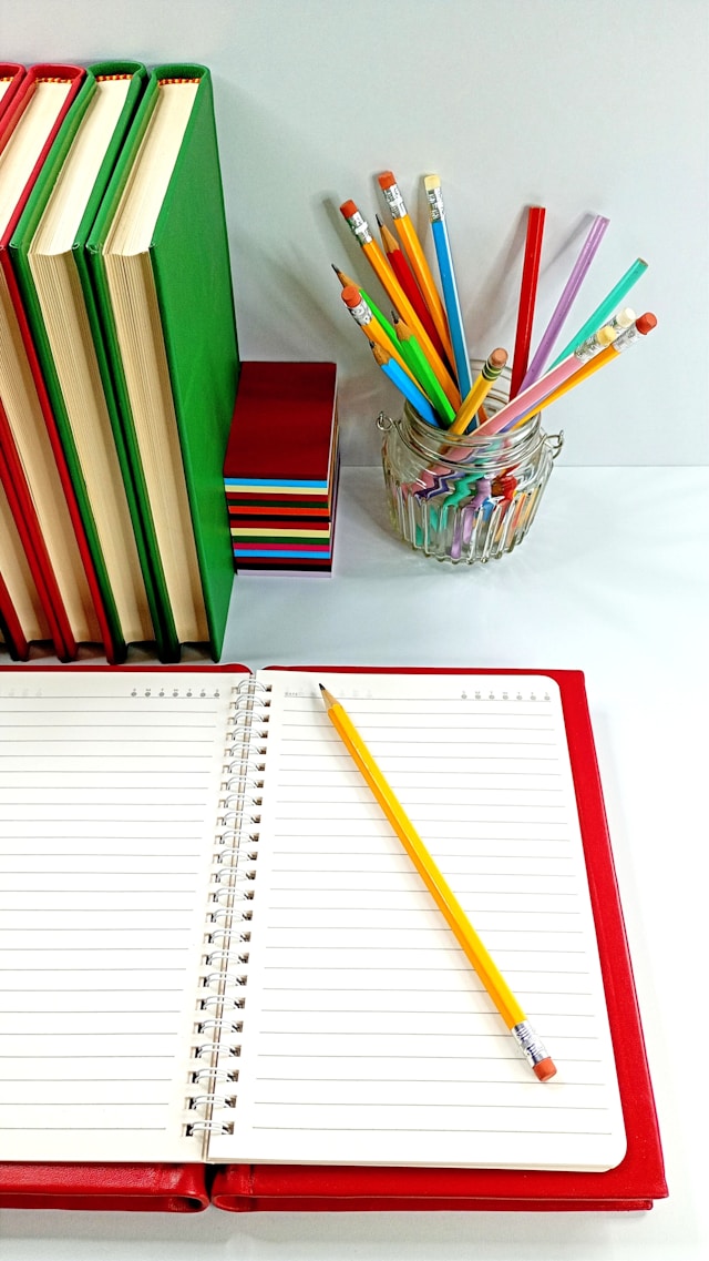 Cahier ouvert à côté d'un pot à crayons